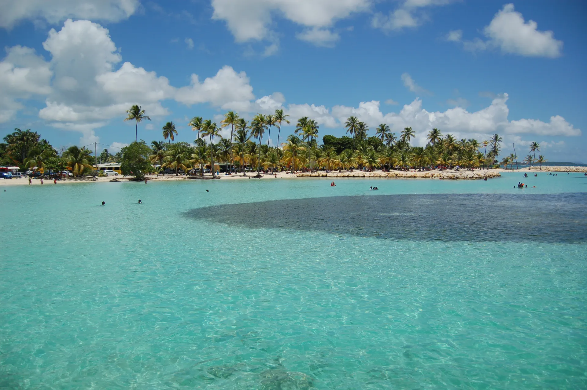 La plage de sable blanc de Sainte-Anne vue depuis la terrasse d'un des gîtes, avec le lagon turquoise en arrière-plan.
