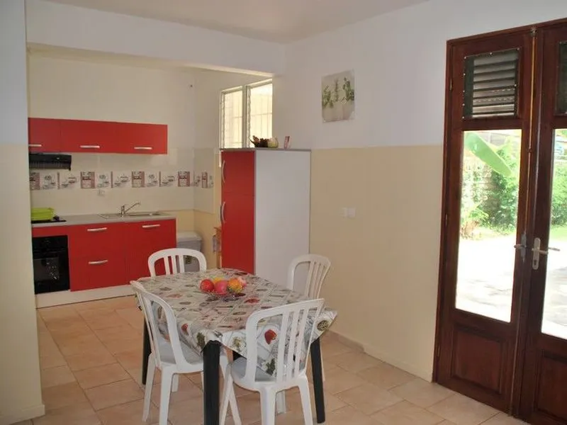 La terrasse couverte de l'appartement Sapotille, ouverte de plain-pied sur la plage et le lagon.